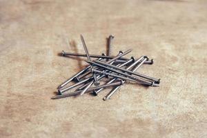 Pile of metal nails on wooden background photo