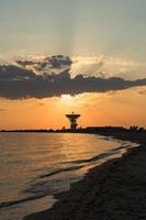 Bright sunset with sun rays on the background of a space antenna. photo