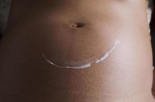 Still life of pregnant woman with smile stretch mark cream photo