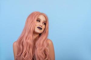 Girl with a doll with pink hair wig. Blue background photo