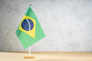 Brazil table flag on white textured wall. Copy space photo