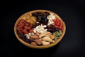 Various types of whole grains and dried fruits on a bamboo tray photo