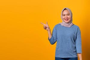 Cheerful attractive Asian woman pointing finger at empty space