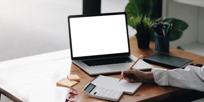 Businesswoman using laptop blank screen while working with calculator photo