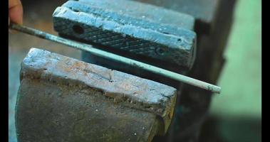 La varilla de metal se sujeta por el mango del tornillo de banco. fotografía de cerca. video