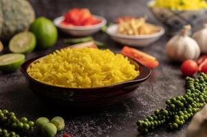 Turmeric rice in a brown cup with spices on black cement. photo