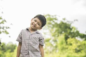 retrato de niño de pie en el parque natural sonriendo a la cámara. foto