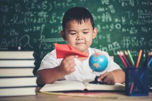 Portrait of boy with a paper plane in classroom photo