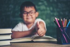 Portrait of a boy with hands thumbs up in the classroom. photo