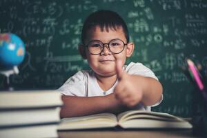 Portrait of a boy with hands thumbs up in the classroom. photo