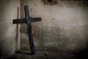 Crucifijo negro contra la pared con cadena de acero colgante y pistola foto