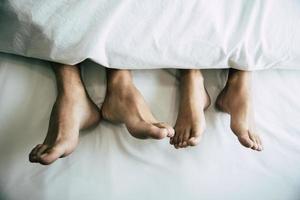 Barefoot of lovers under blanket in bedroom photo