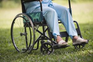 Cerrar solitaria anciana sentada en silla de ruedas en el jardín foto