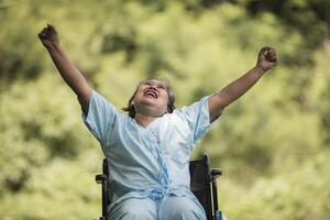 Anciana solitaria sentada en silla de ruedas en el jardín en el hospital foto