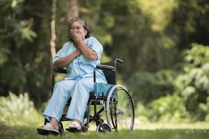 Lonely elderly woman sitting sad feeling on wheelchair at garden photo