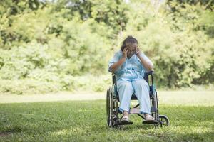 Lonely elderly woman sitting sad feeling on wheelchair at garden photo