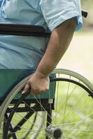 Cerrar solitaria anciana sentada en silla de ruedas en el jardín foto