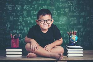 Thoughtful little boy with book near a school board photo
