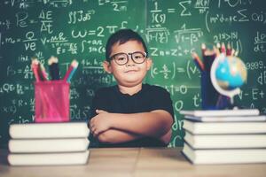 Thoughtful little boy with book near a school board photo