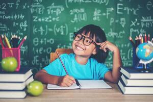 Thoughtful little girl with book near a school board photo