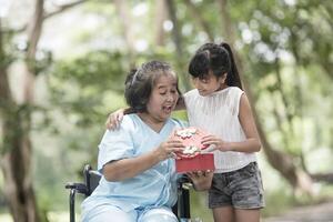 Granddaughter have surprise to grandmother sitting on wheelchair. photo