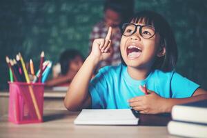 Thoughtful little girl with book near a school board photo