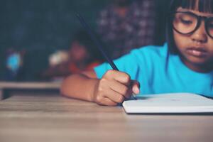 girl with crayon drawing at lesson in the classroom photo
