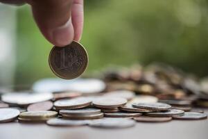 concepto de ahorro de dinero. mano poniendo dinero pila de monedas foto