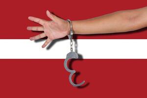 handcuffs with hand on Latvia flag photo