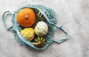 Autumn composition with assorted pumpkins in eco string bag photo