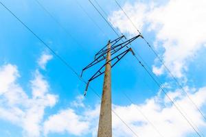 High-voltage transmission line with concrete supports on the background of blue sky photo
