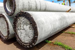 Unloading of concrete high-voltage poles at the construction site using a lifting crane photo