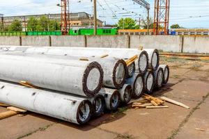Unloading of concrete high-voltage poles at the construction site using a lifting crane photo