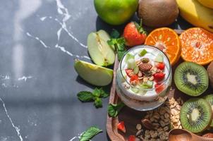 Primer plano de yogur de nutrición con muchas frutas en la mesa foto