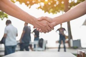 Closed up of hand shake with people in background photo