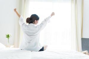 Back view of woman stretching in morning after waking up photo