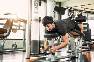 Hombre de deporte asiático estirando y levantando peso con dos piernas foto