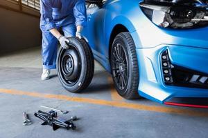 Mecánica de automóviles cambiando el neumático en el garaje del taller de reparación de automóviles