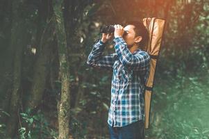 Man with binoculars telescope in forest looking destination photo