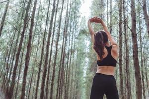 Women stretching arms and breathing fresh air in middle of pinewood photo