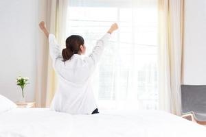 Vista posterior de la mujer que se extiende por la mañana después de despertarse en la cama foto