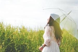 Asian woman in white dress holding umbrella  in rapeseed field photo