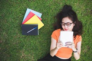 Happy Asian woman using tablet when relaxing in park photo