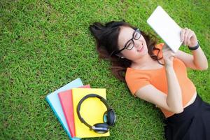 mujer tendida en el césped y usando la tableta, concepto de educación foto