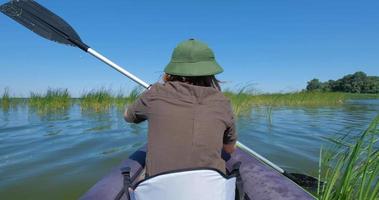 giovane donna viaggiatrice con cappello nuotare in kayak. video