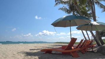 Beautiful tropical sea beach with umbrella chairs and a blue sky video