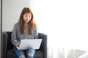 mujer asiática joven que usa la computadora portátil para el ocio. foto