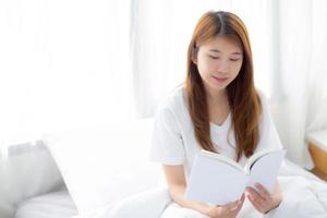 joven asiática relajarse sentado leyendo un libro en el dormitorio. foto