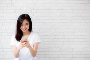 Young asian woman using phone and smiling. photo