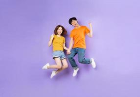 Portrait of a couple jumping up, isolated on purple background photo